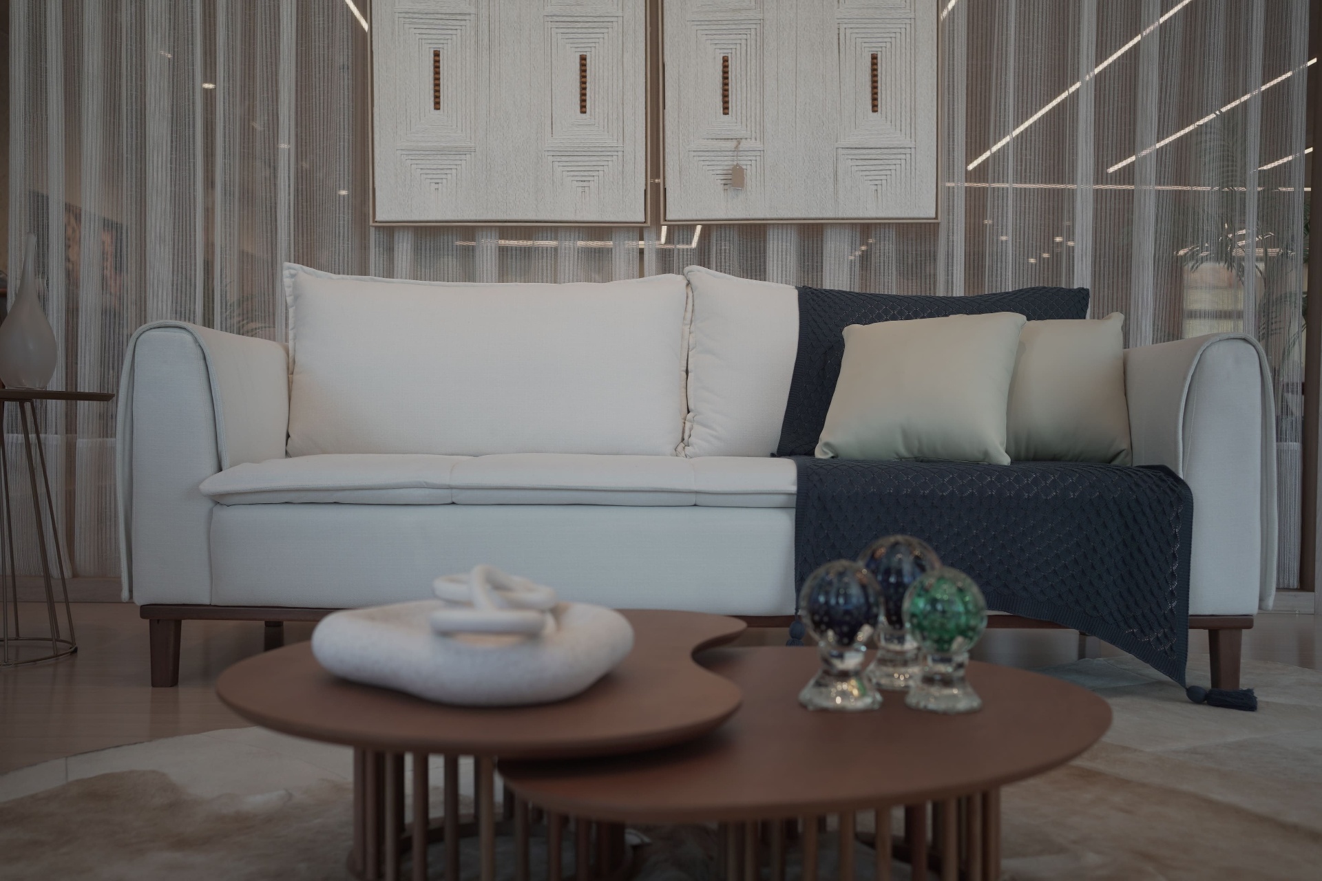 Sofá branco com manta cinza e mesa de centro orgânica